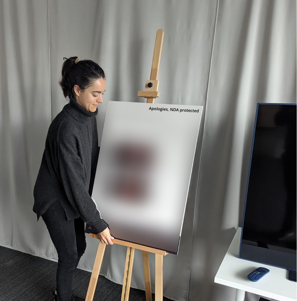Lucrecia standing on a ladder, reaching up to finish hanging a curtain backdrop in an office space